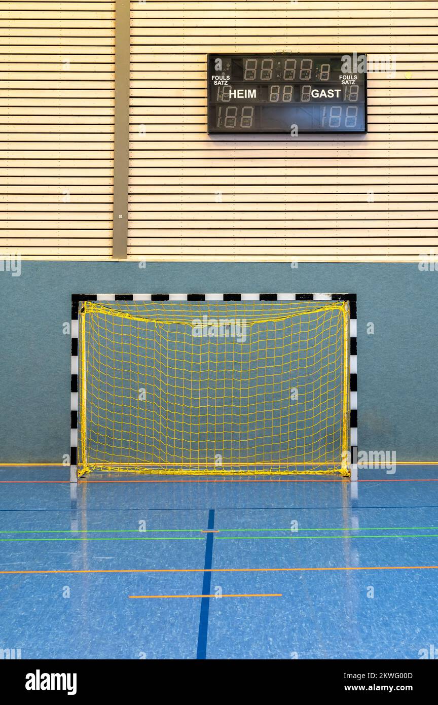 Modern sports hall with handball goal and scoreboard in German language with the words home and guest Stock Photo