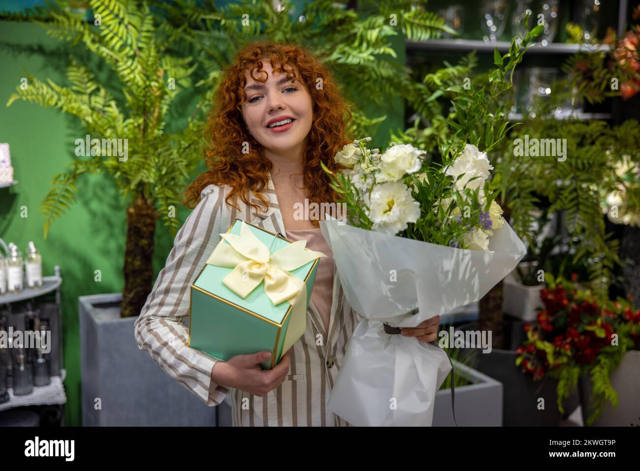 Cute smiling young woman with a gift box in hands Stock Photo