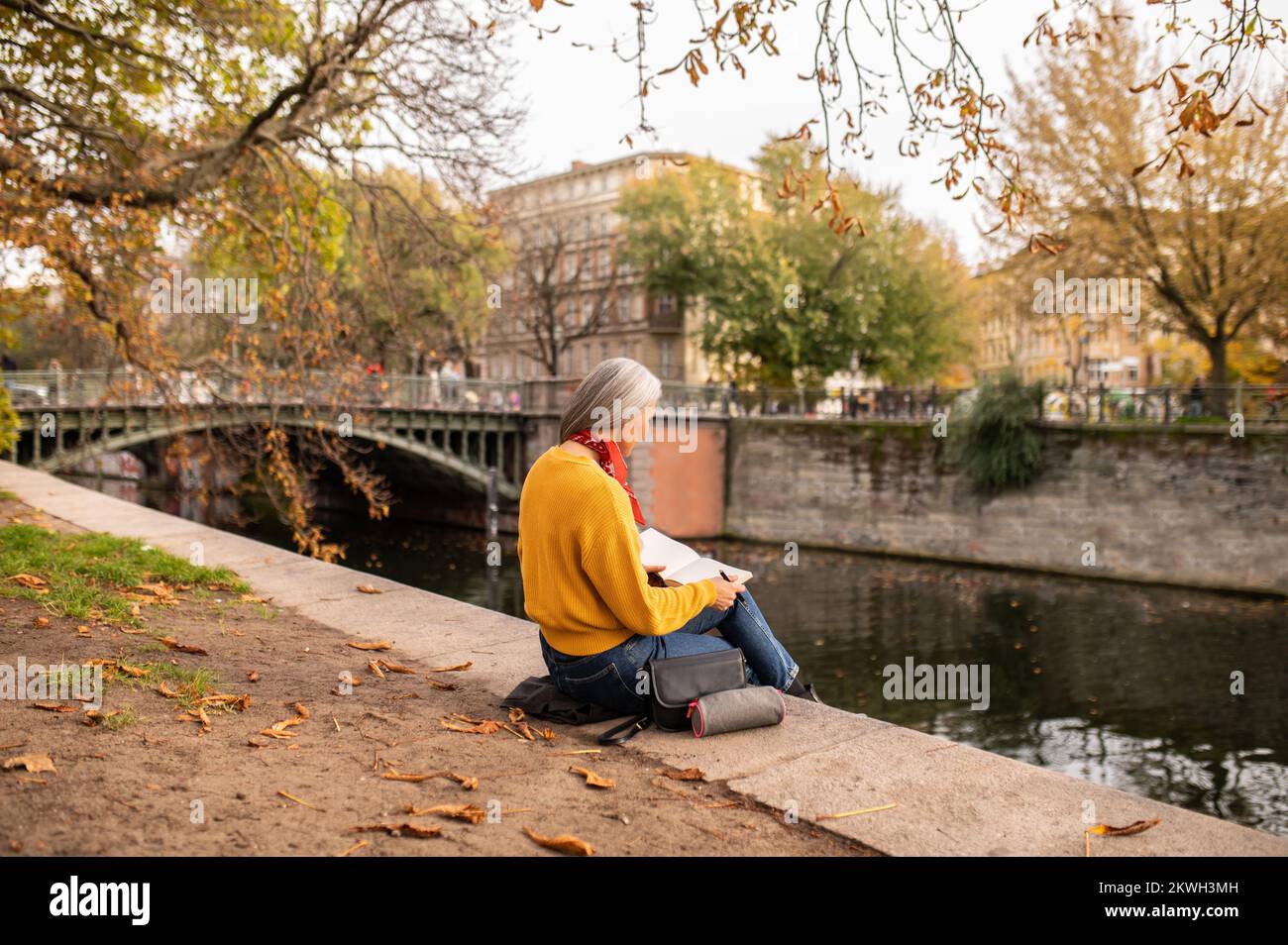 Woman sitting on the river bank and making notes Stock Photo - Alamy