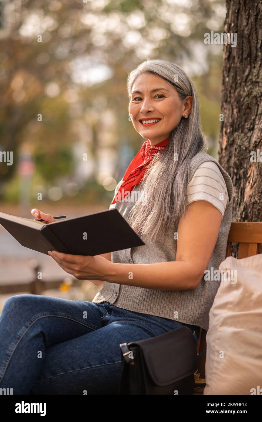 Pretty inspired woman sitting on a bench in the park Stock Photo