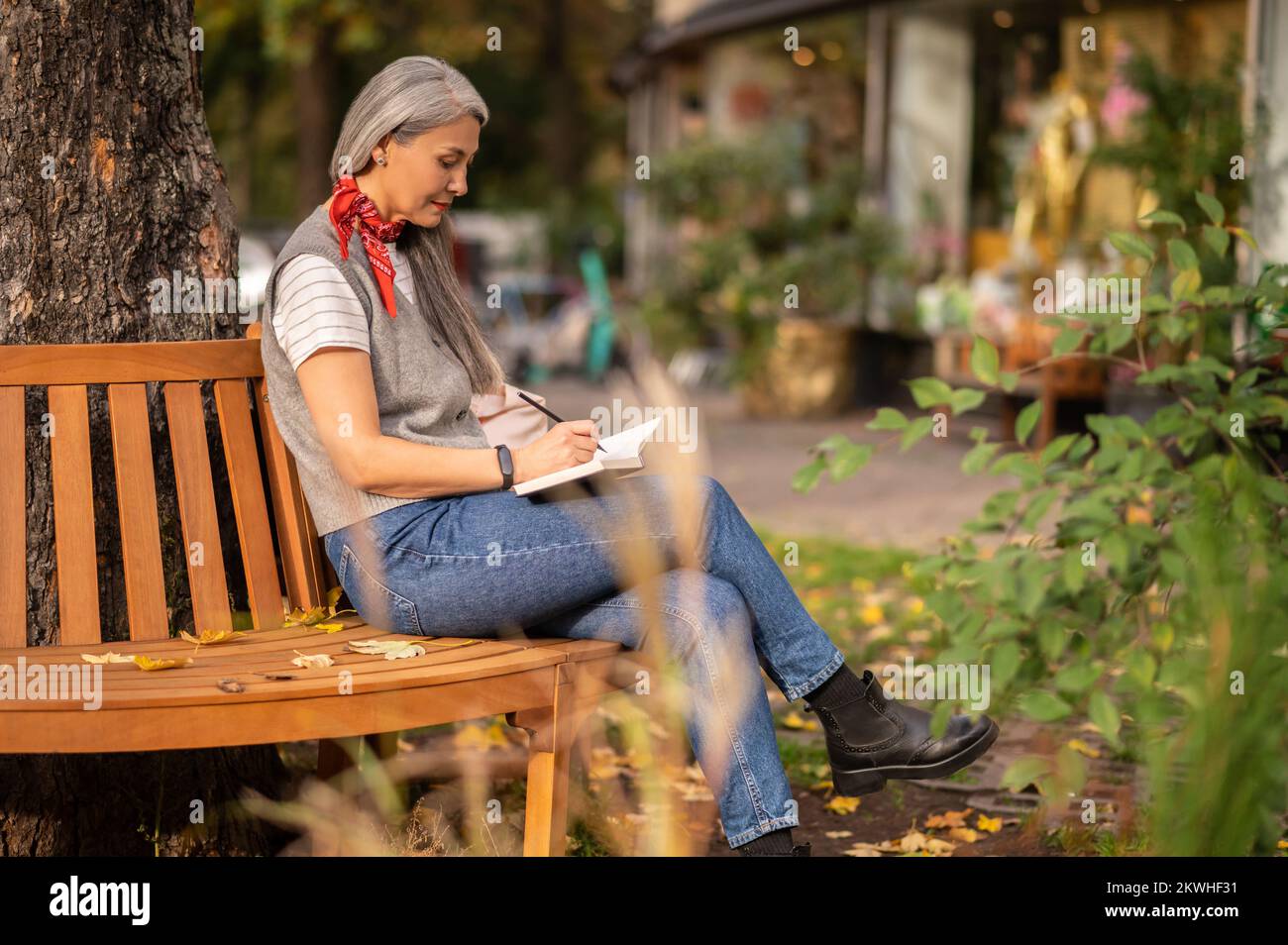 Woman sitting on a bench with a notebook in and looking involved Stock Photo