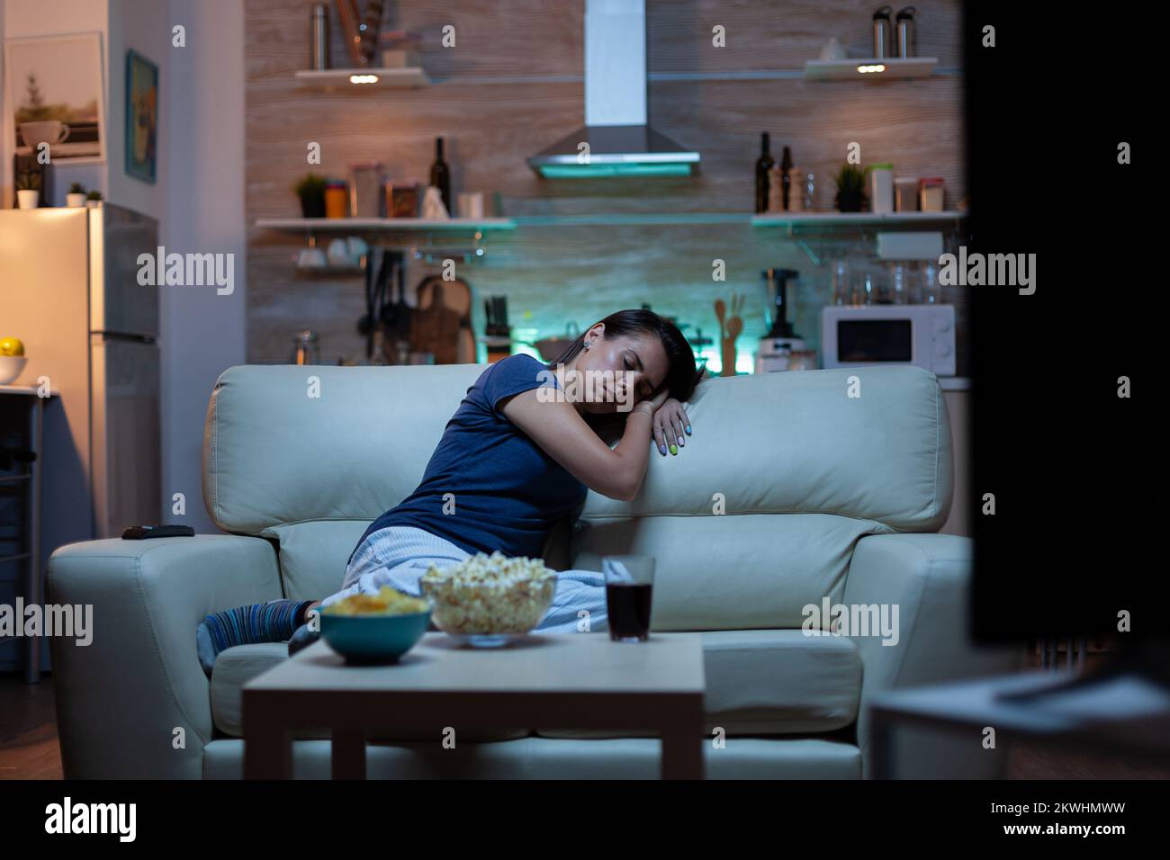 Woman falling asleep on sofa in front TV. Tired exhausted lonely sleepy