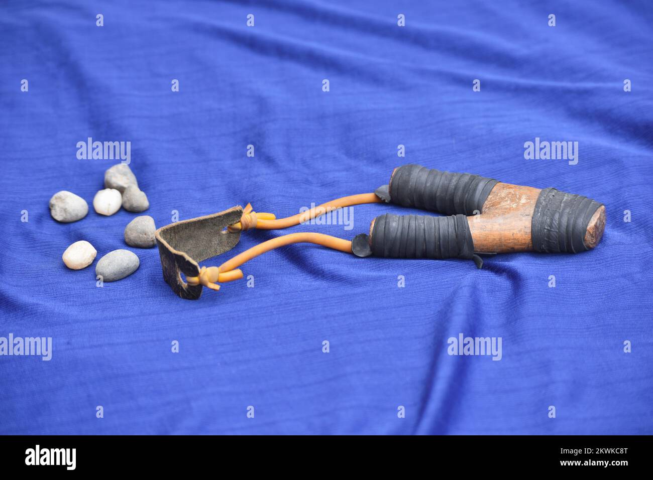 Catapult Gulel SlingShot - Isolated wooden slingshot and stones against on blue background, Pune, Maharashtra, India Stock Photo