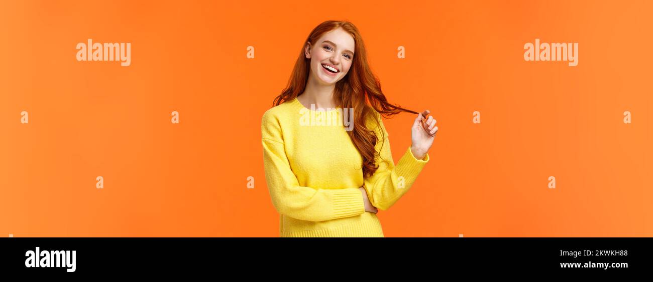 Carefree good-looking, smiling toothy redhead woman, girl with ginger hair laughing as chatting friends, rolling curl on hair, tilt head and smiling Stock Photo