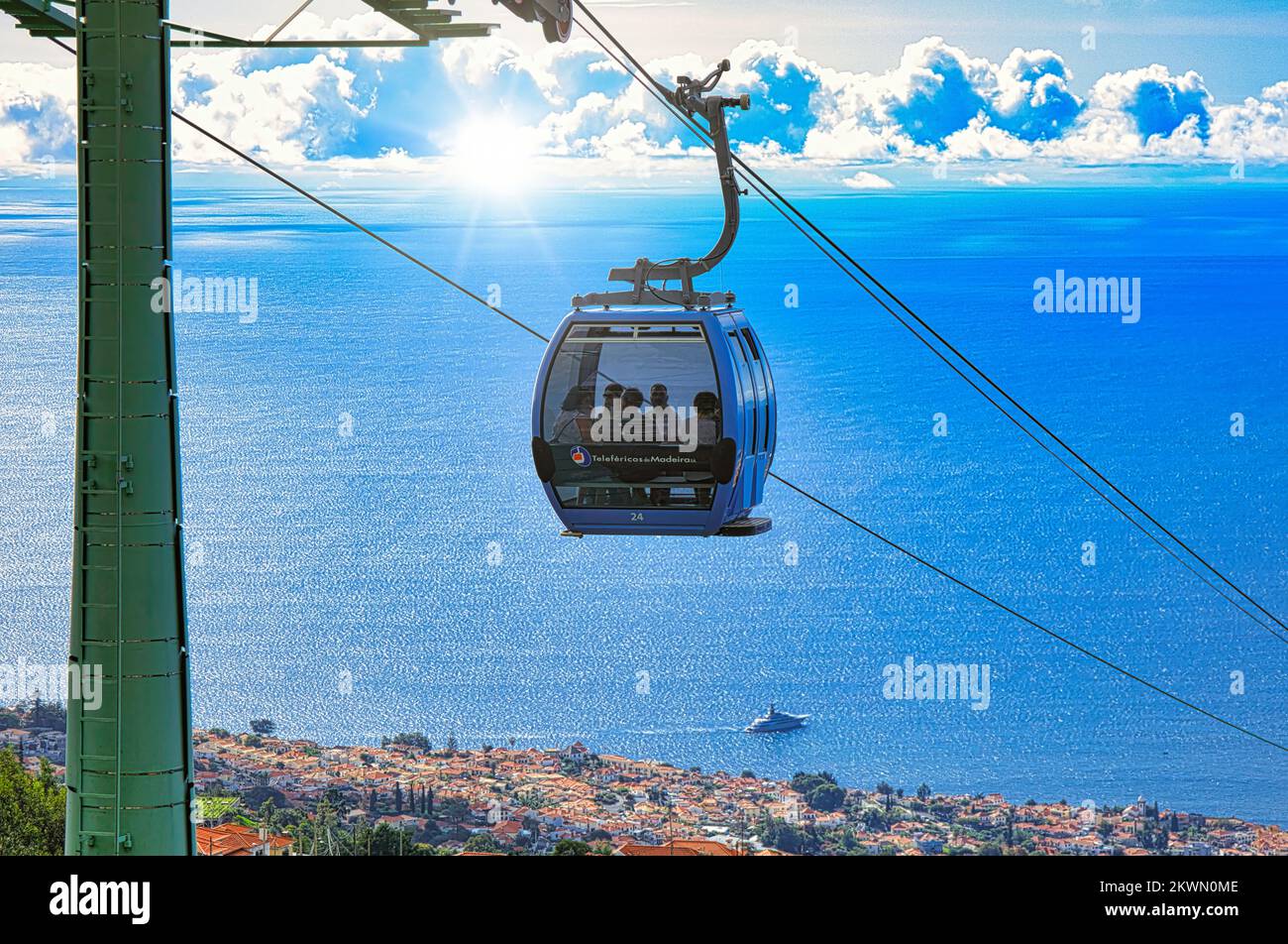 Madeira island - Cable car at Monte high above the rooftops and streets of Funchal the capital city with sunburst through clouds. Stock Photo