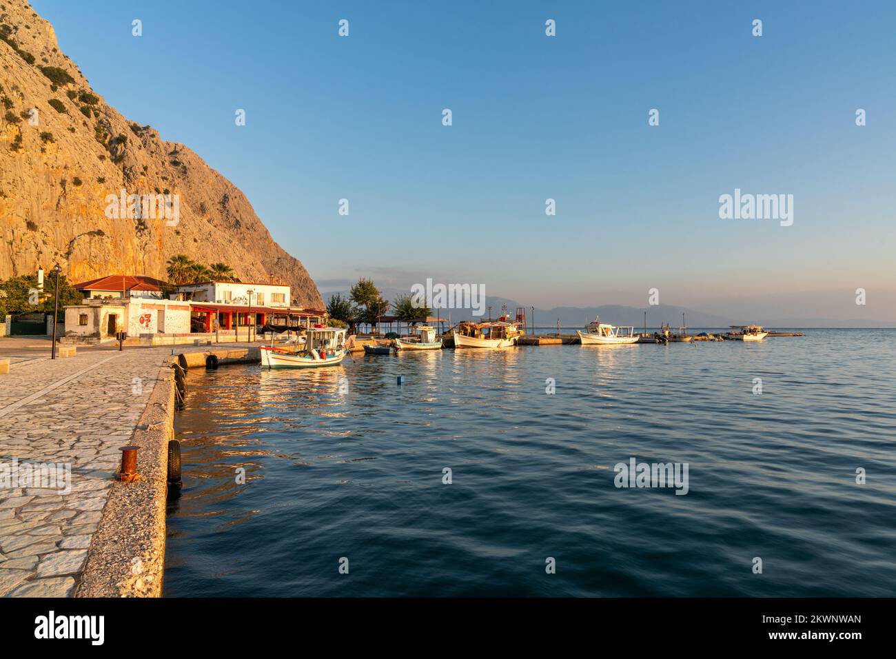 The small fishing hamlet of Kryoneri on the Gulf of Corinth with Vasarova mountain at sunset Stock Photo