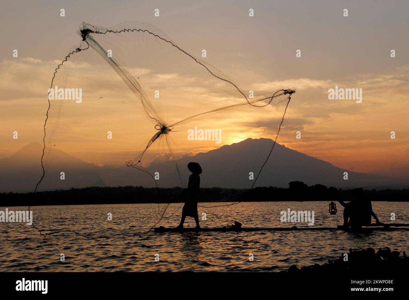 silhouette of a fisherman throwing a net in a reservoir at dusk Stock Photo  - Alamy