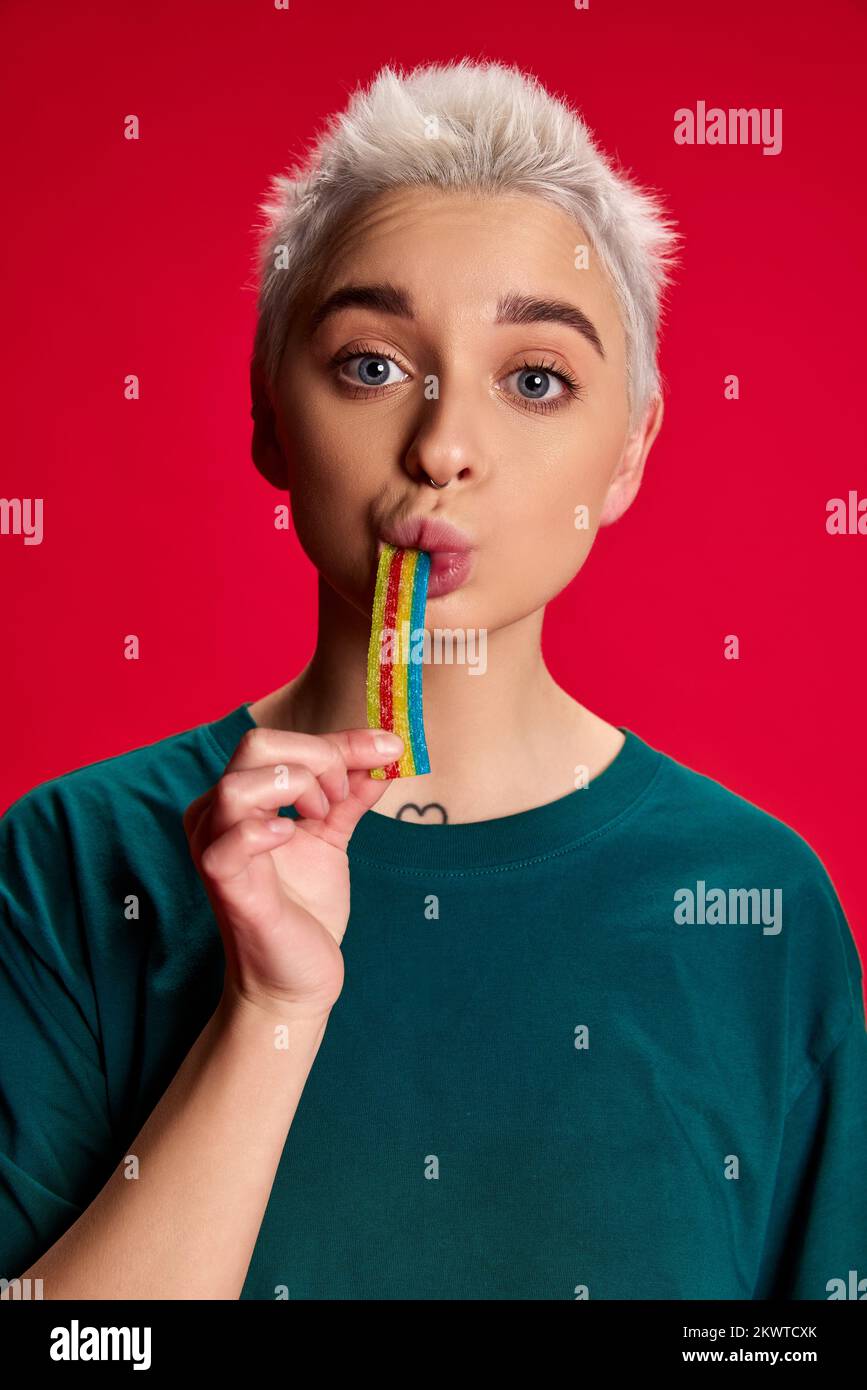 Portrait of young stylish woman with short hair posing, eating jelly