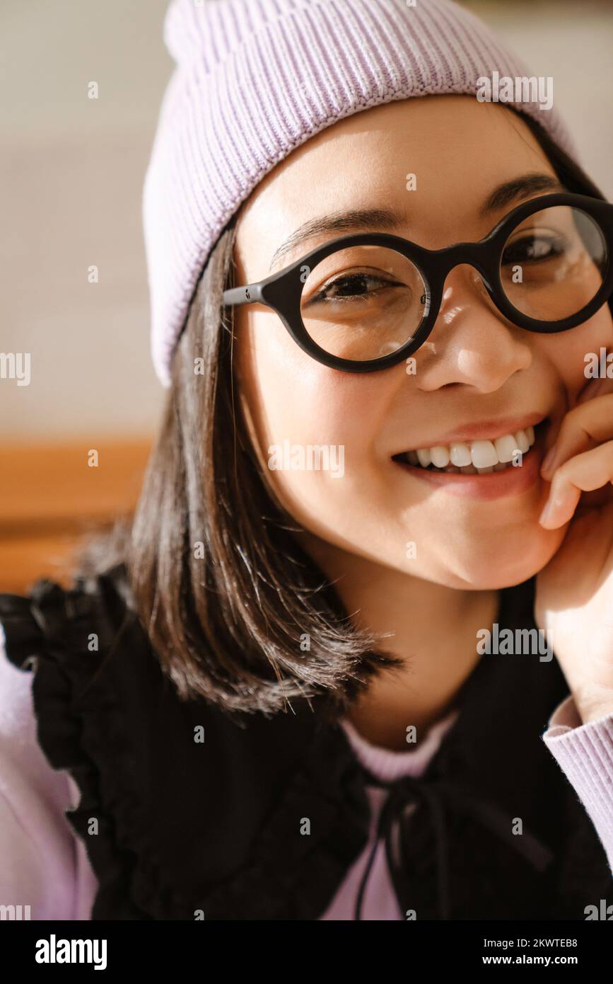 Young asian woman in eyeglasses smiling and looking at camera indoors Stock Photo