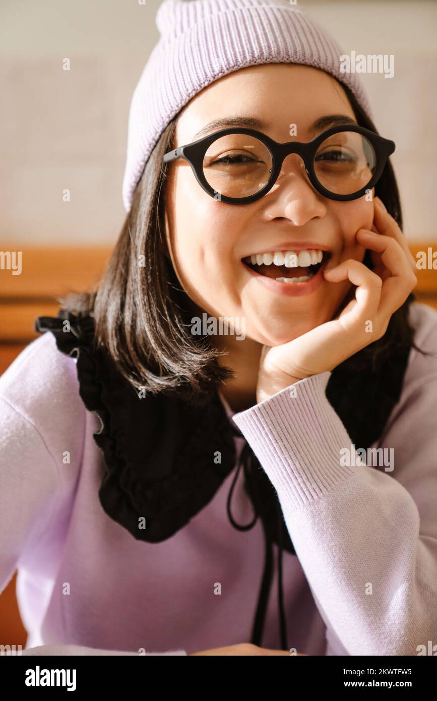 Young asian woman in eyeglasses smiling and looking at camera indoors Stock Photo