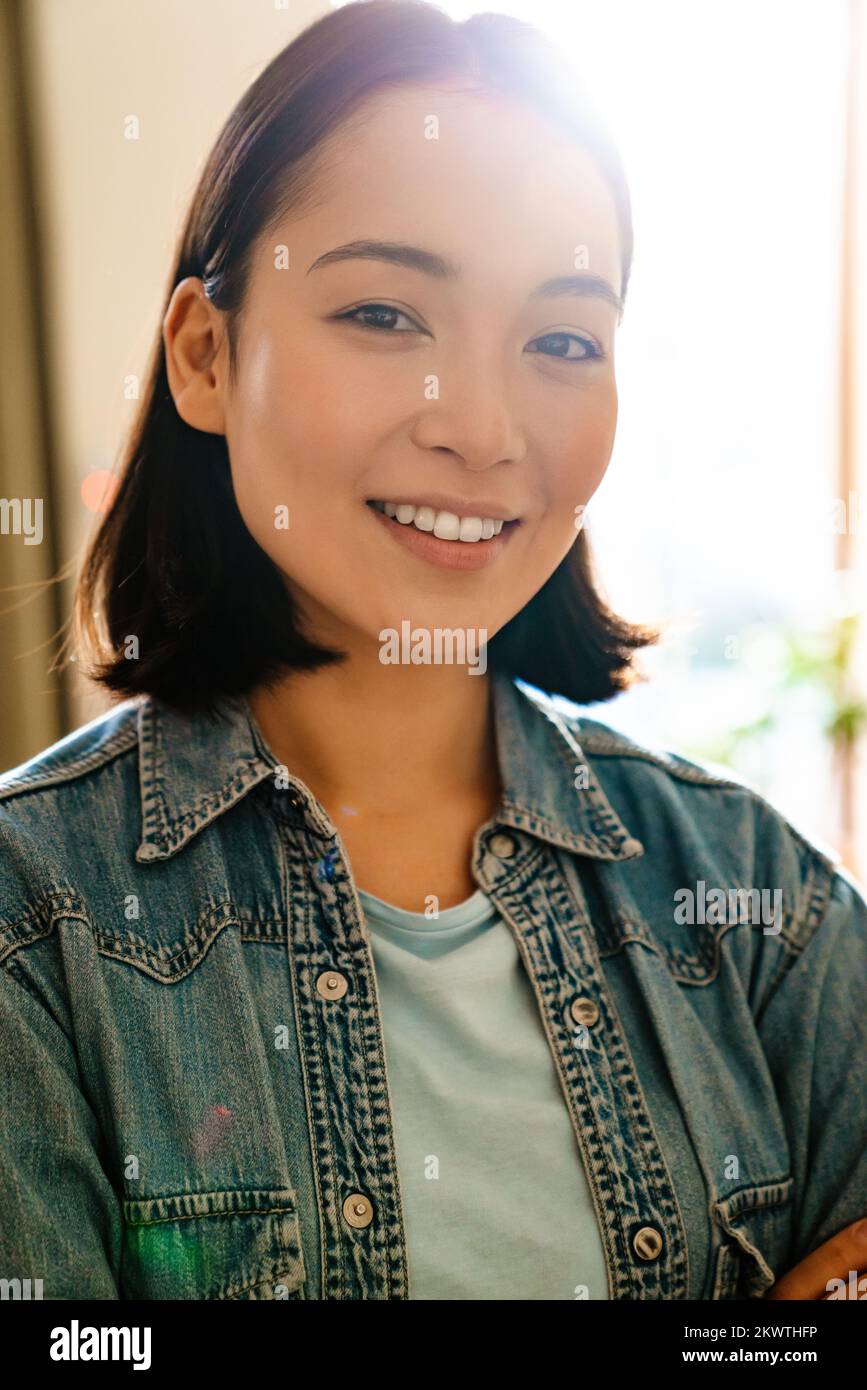Young asian woman wearing denim shirt smiling and looking at camera ...