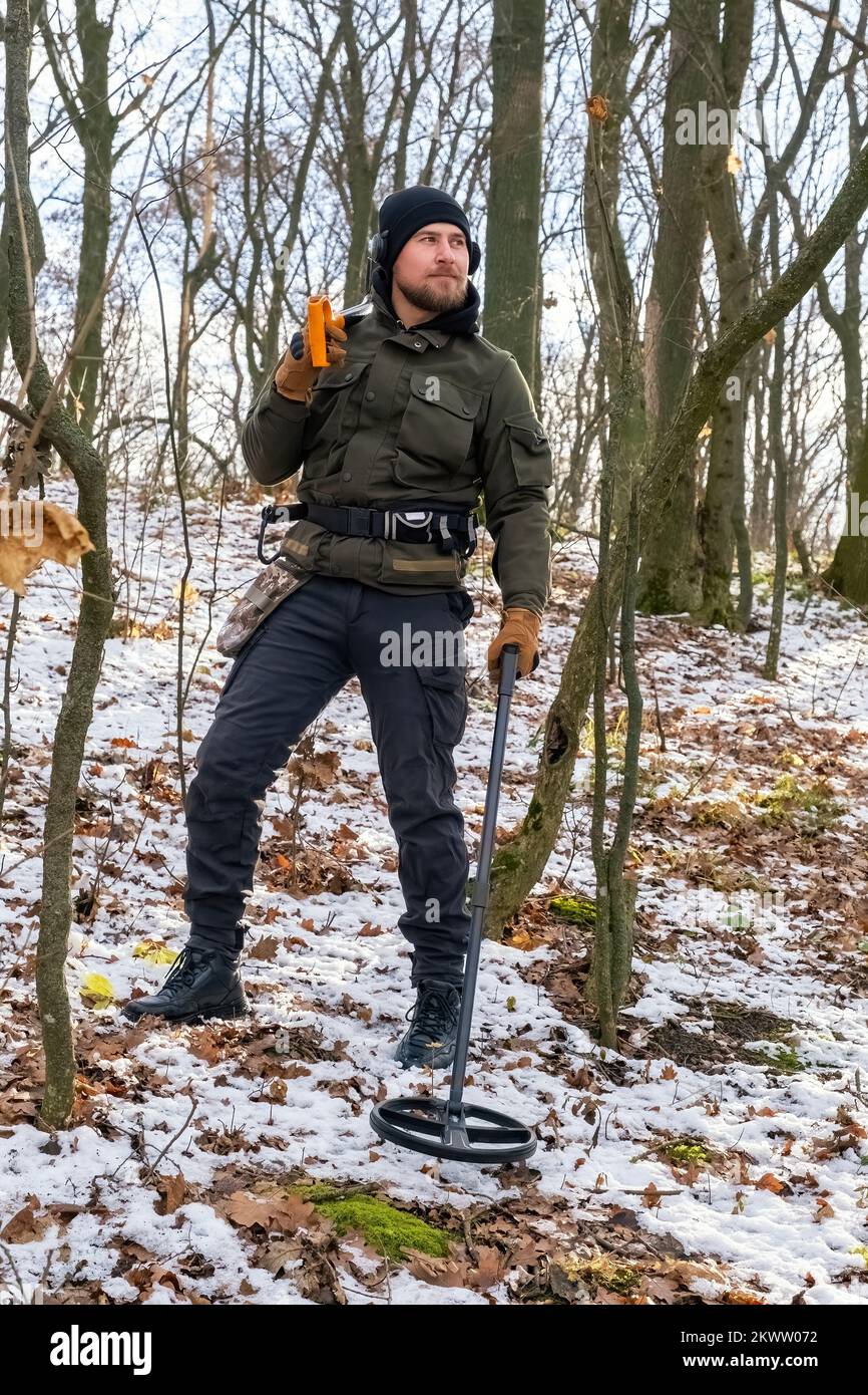 Man with metal detector and shovel in snowy forest Stock Photo
