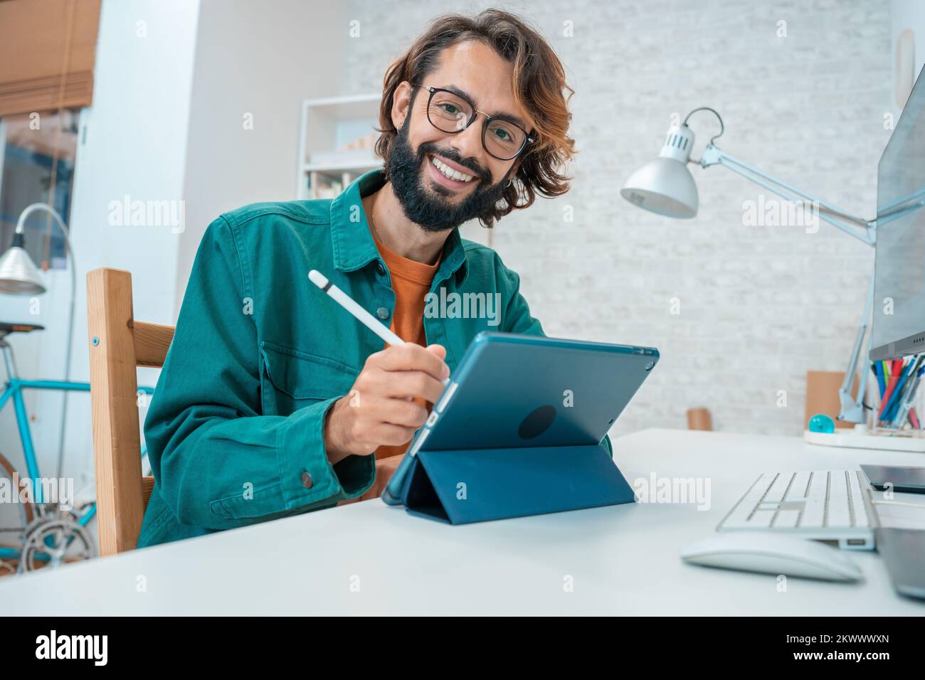 Young designer looking at camera while working with graphics tablet Stock Photo