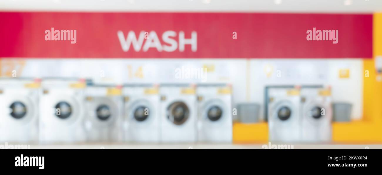 Blur background of of qualified coin-operated washing machines in a public store. Concept of a self service commercial laundry and drying machine in a Stock Photo