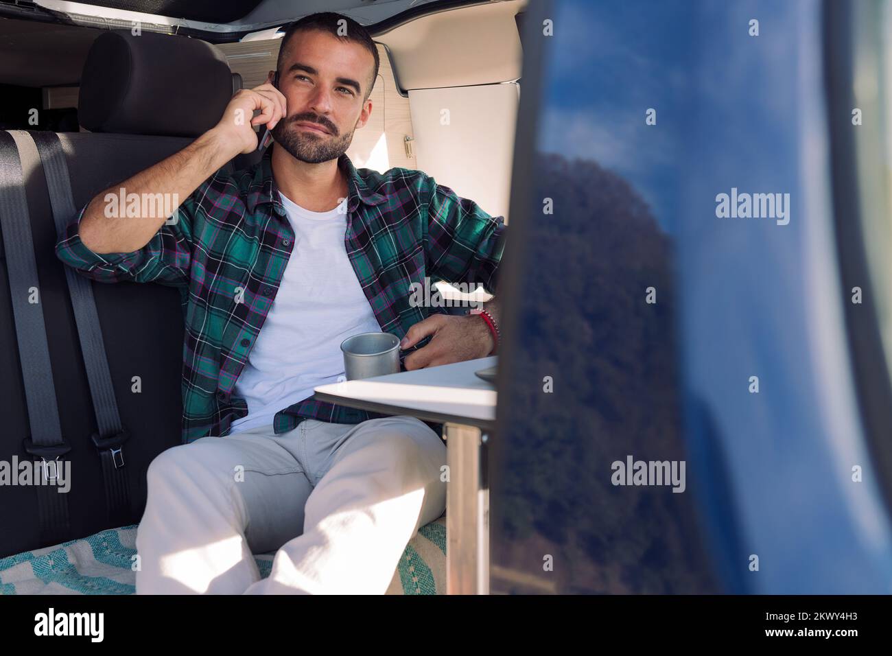 man sitting inside his camper van talking on phone Stock Photo