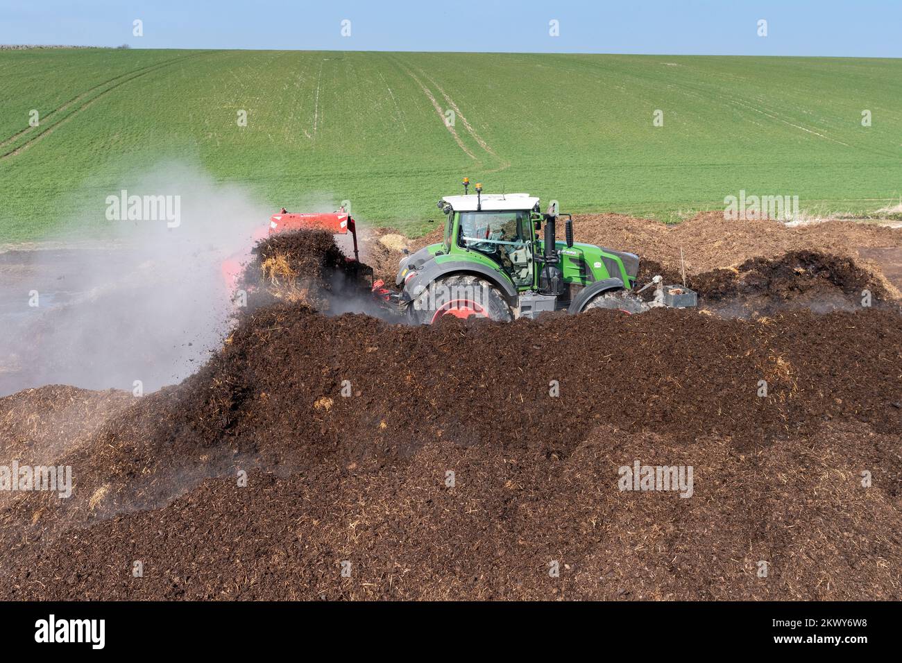 Turning a manure heap over to make compost to spread on farmland, which
