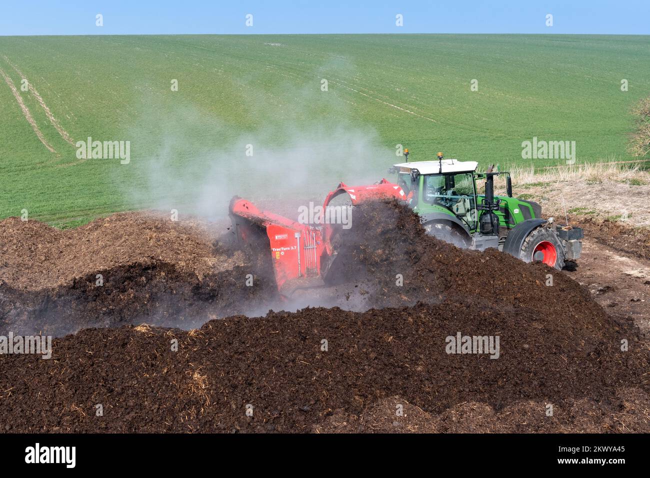 Turning a manure heap over to make compost to spread on farmland, which