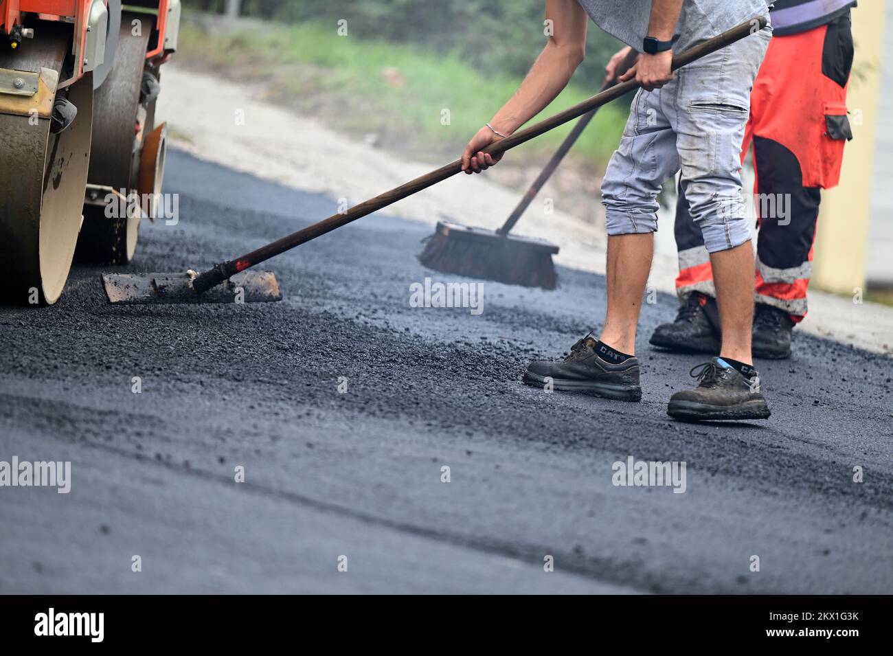 Feet of construction workers paving a road Stock Photo