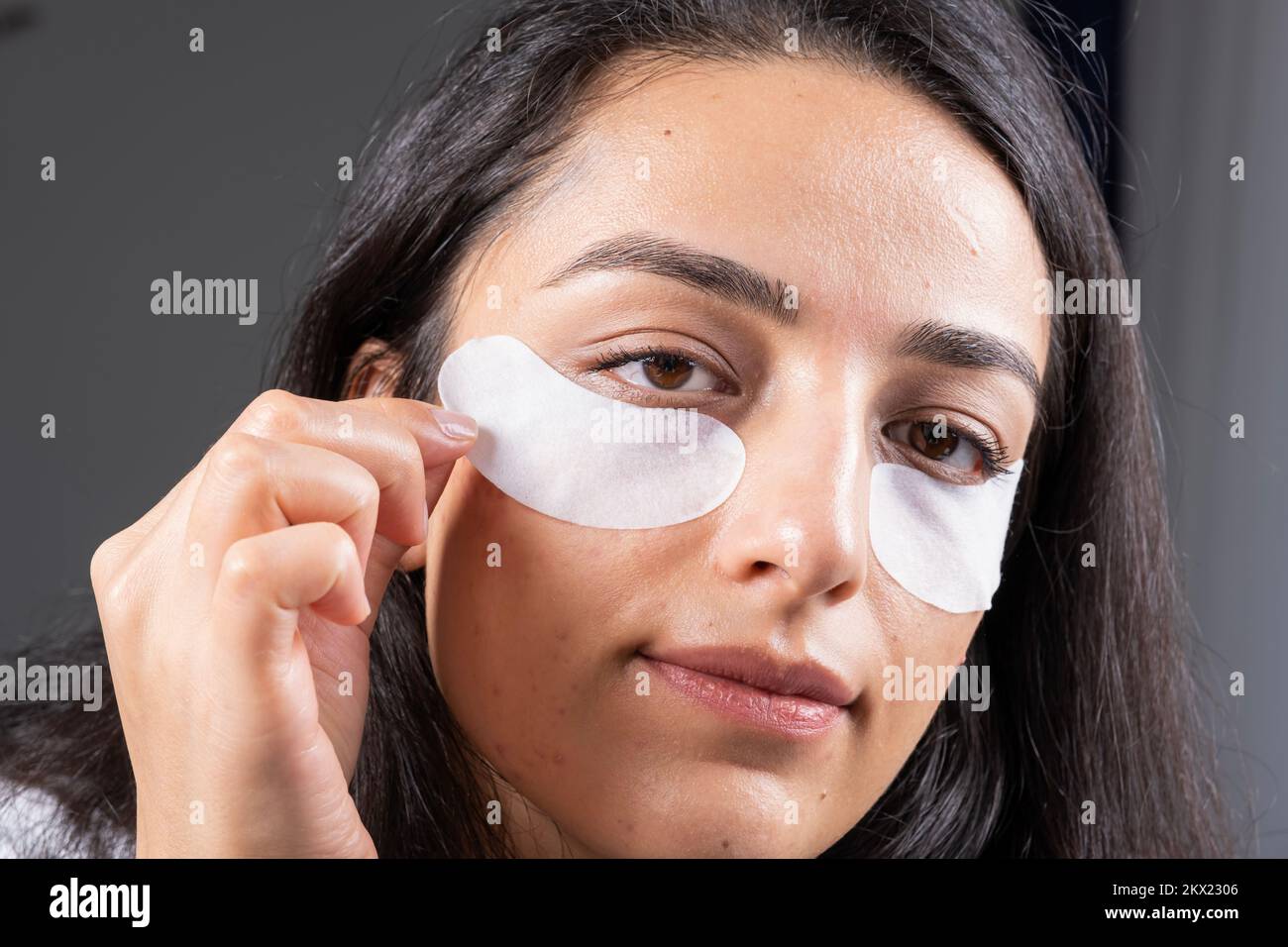 Using under eye patch, close up no make up, natural face. Caucasian brunette millennial woman, fight with dark circles. swelling, wrinkles, wellbeing. Stock Photo