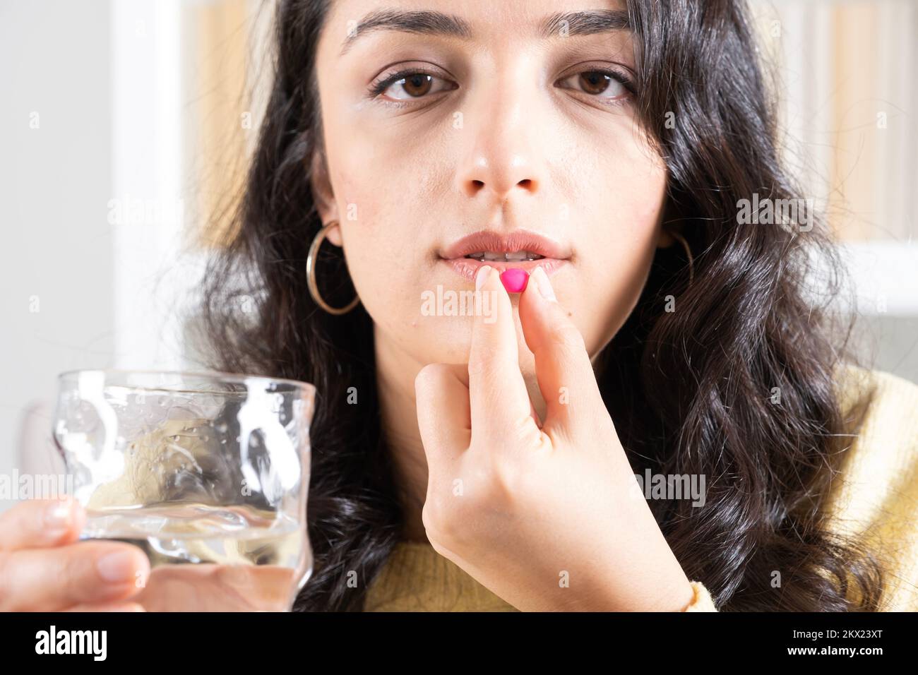 Taking pill, close up front view of woman taking pill. Holding antibiotic or antidepressant or vitamin or contraceptive medicine tablet. Stock Photo