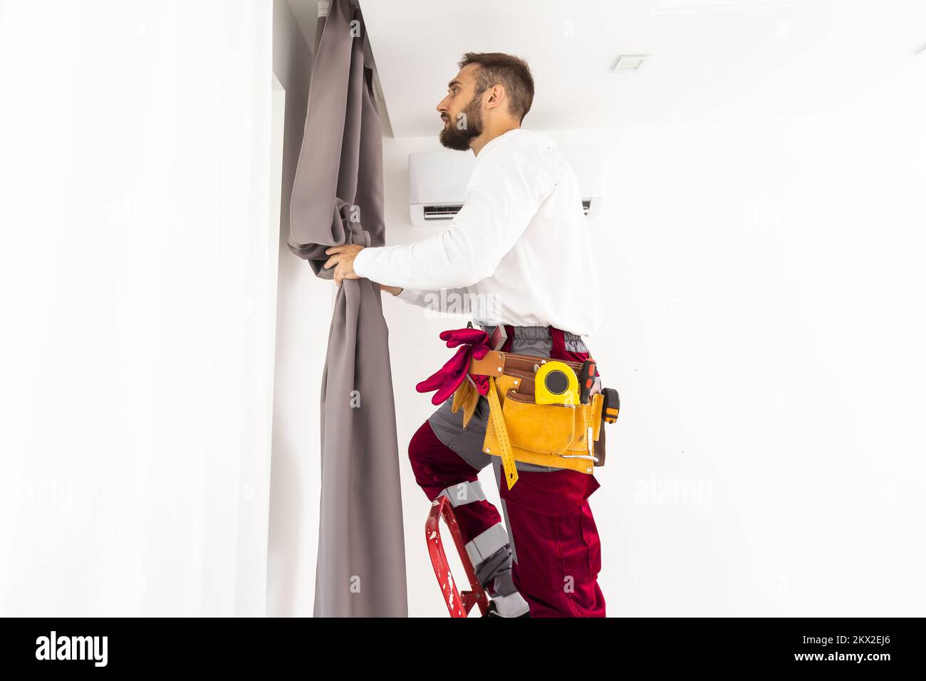 Man hanging window curtain indoors. Interior decor element Stock Photo