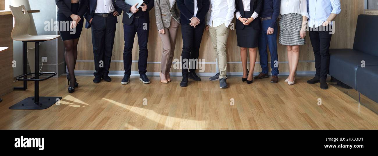 Banner image of legs of different business people standing in row in modern loft office. Stock Photo