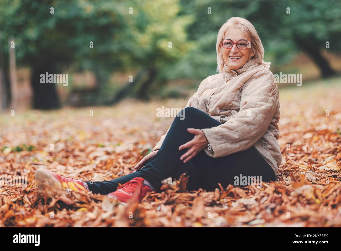 Happy beautiful senior woman enjoying nature in park in autumn Stock Photo