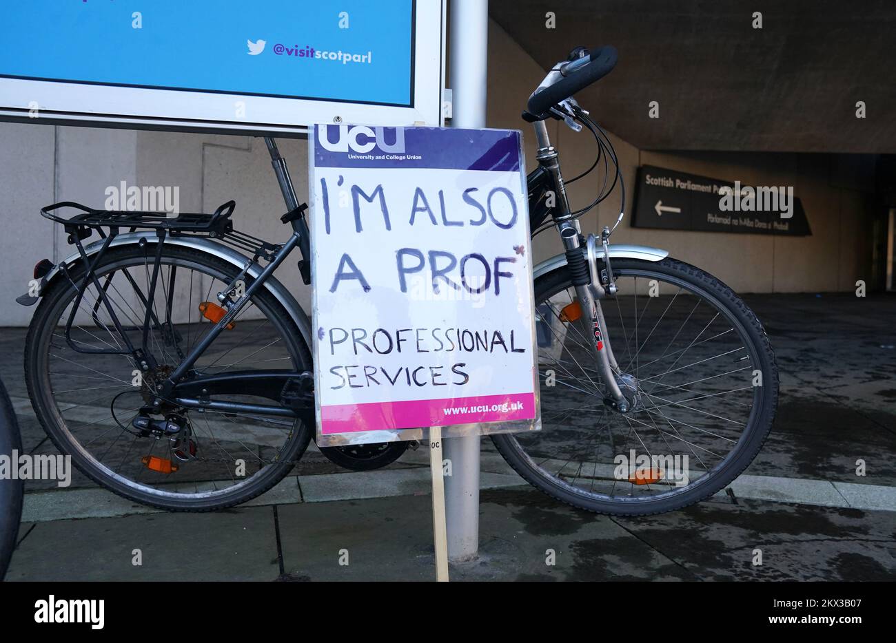A placard sits against a bike as people take part in a rally outside the Scottish Parliament, Edinburgh, as members of the University and College Union (UCU) take part 24-hour stoppage among university staff in an ongoing dispute over pay, pensions and conditions. Picture date: Wednesday November 30, 2022. Stock Photo