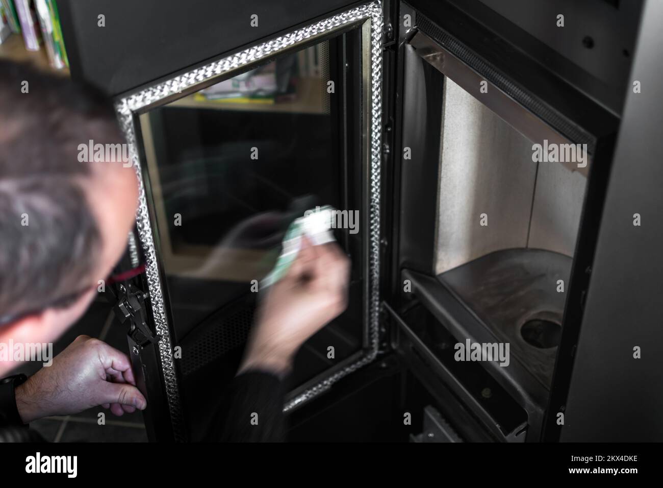 Man cleaning the ash on the glass of a pellet or wood stove with a