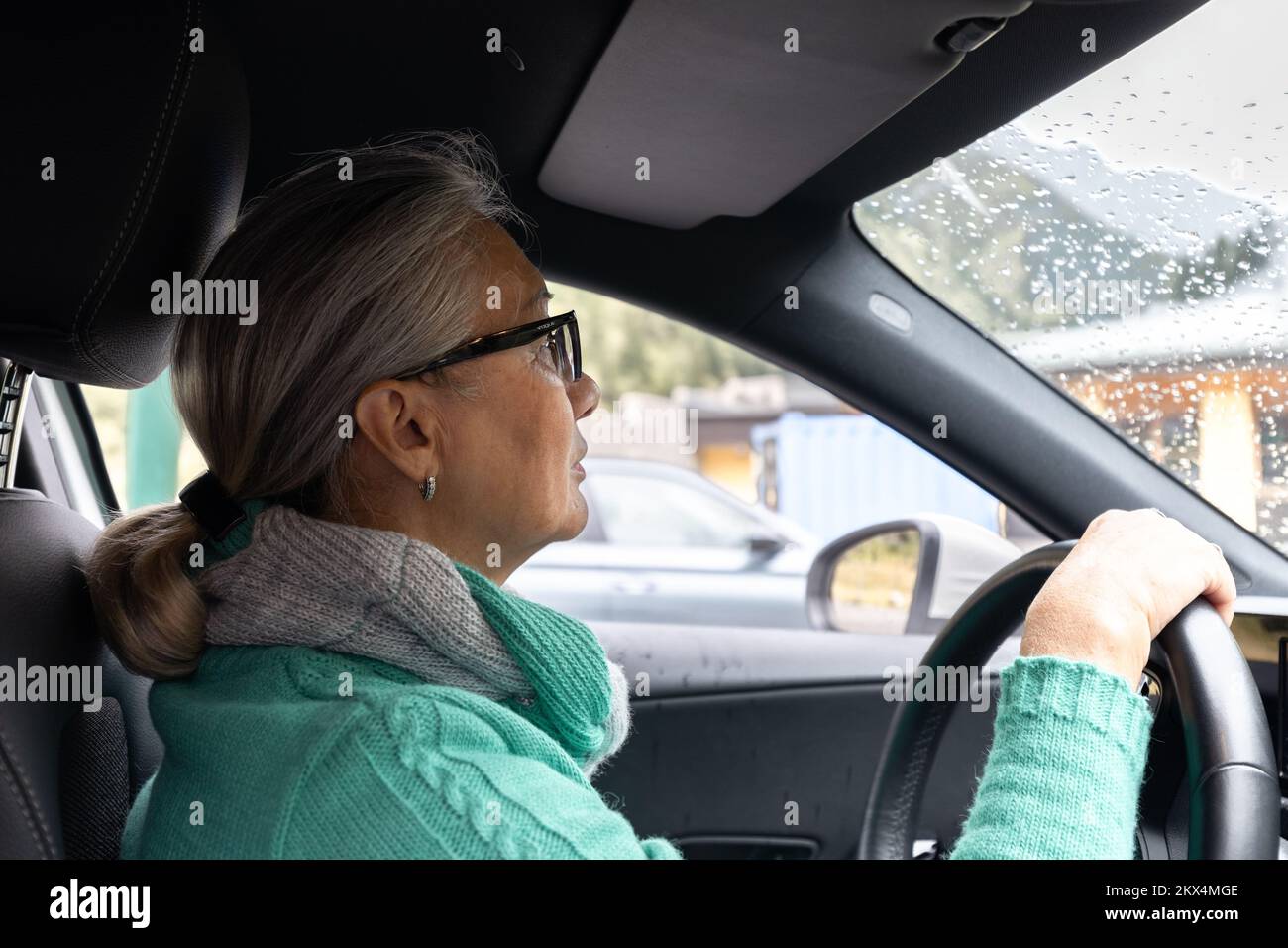 The gray-haired lady drives her own car Stock Photo