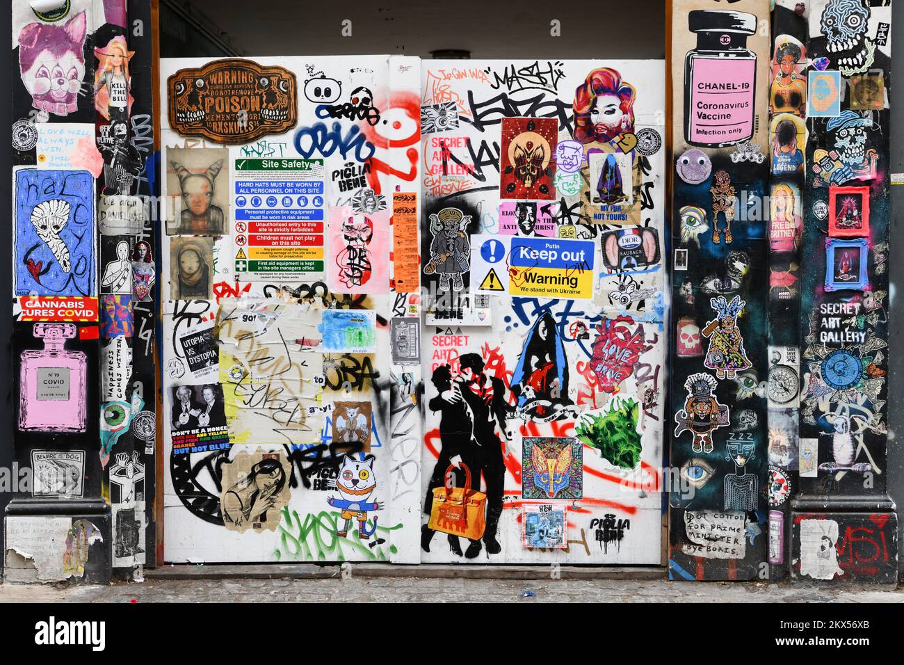 gates covered in graffiti, paste-ups, stickers and posters on Cheshire Street, Shoreditch, London Stock Photo