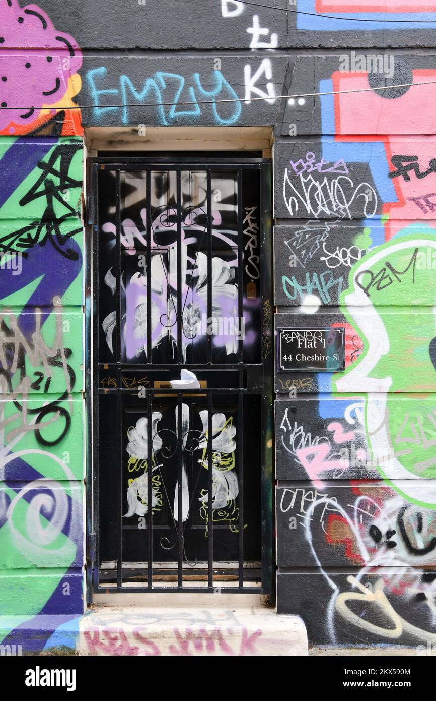 Black flat door numbered flat 1 44 Cheshire Street and covered in graffiti in Shoreditch, London Stock Photo
