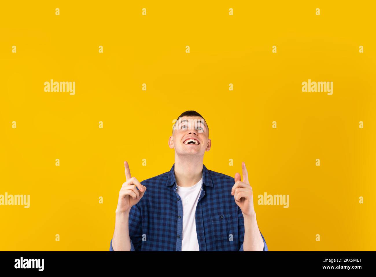 Excited caucasian guy pointing up with both hands at free space for advertisement or text, yellow background Stock Photo