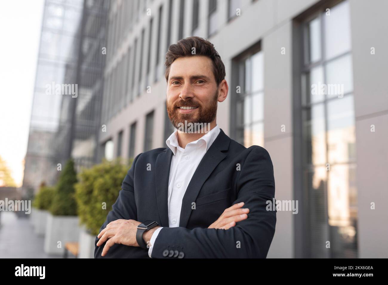 Confident glad young european male ceo manager with beard crossed his arms over chest, looks at empty space Stock Photo
