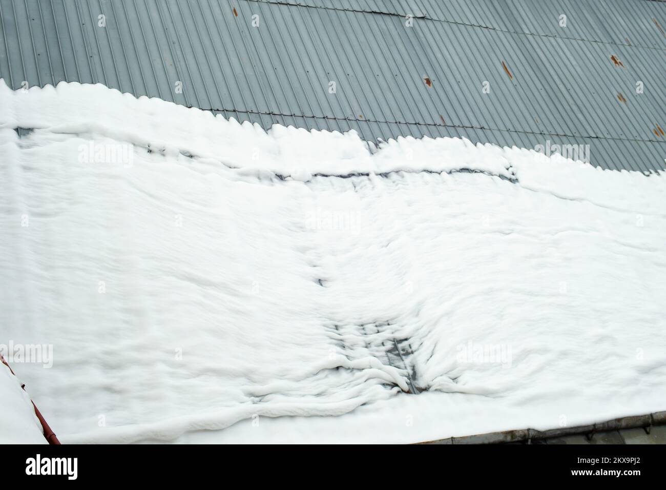 snow melting on a metal roof, accident hazard Stock Photo Alamy