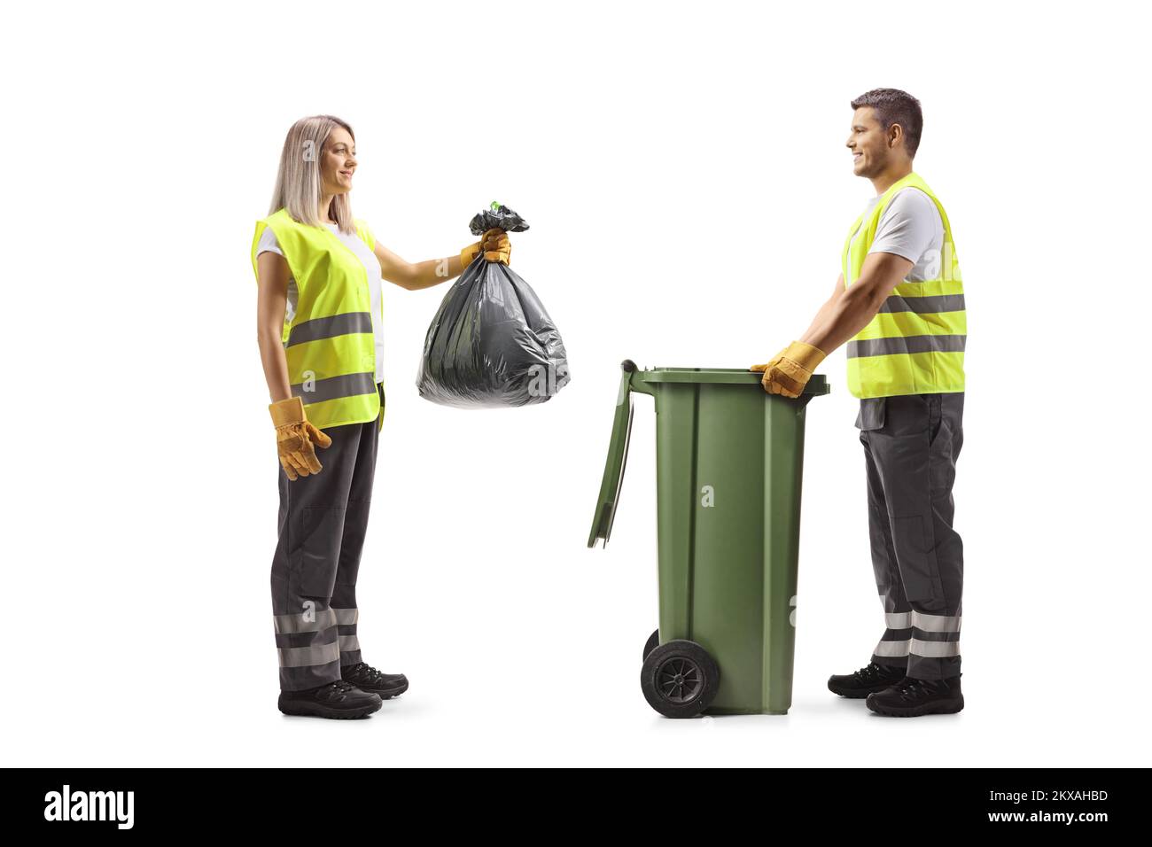 Full length profile shot of a male and female waste collectors putting a bag in a bin isolated on white background Stock Photo