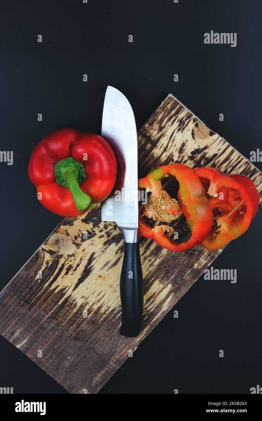 Wooden Cutting Board with Raw Vegetables pepper on Rustic Cutting Board. Sliced pepper and knife with wooden handle on Rustic Cutting Board Stock Photo