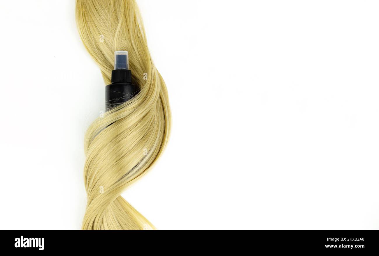 Different professional hairdresser tools hair spray and strand of blonde hair on white background, flat lay. Hair care spa concept. Hairdresser salon Stock Photo
