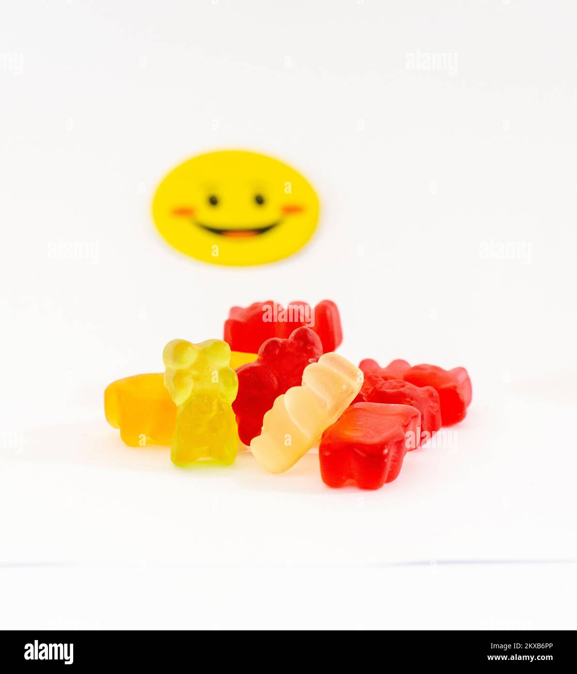 Group of colored gummy bear candy and yellow smiley stick isolated on a white background. Family of jelly bears Stock Photo