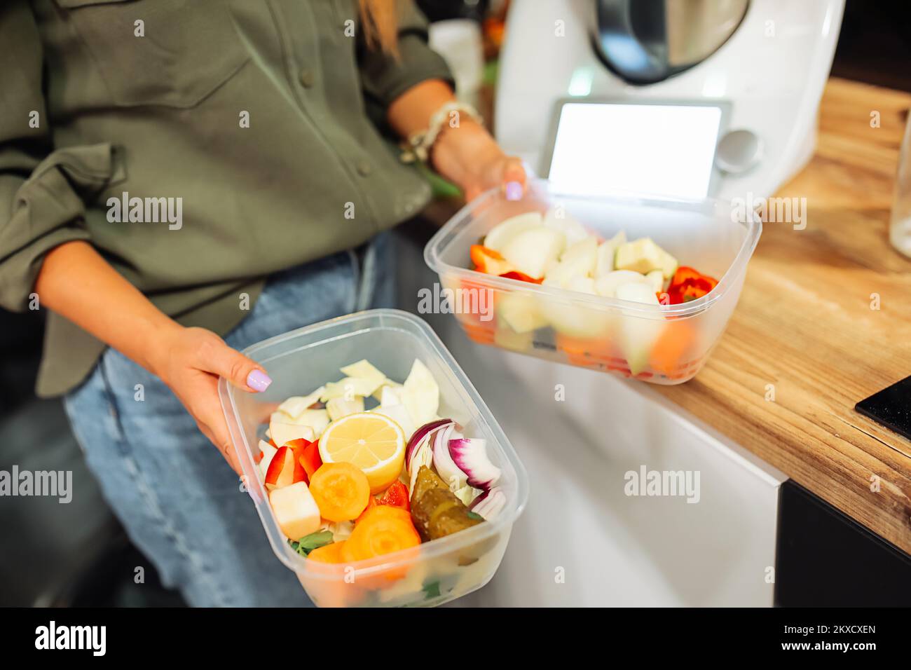 Hands of woman holding plastic containers with cutting fruits and