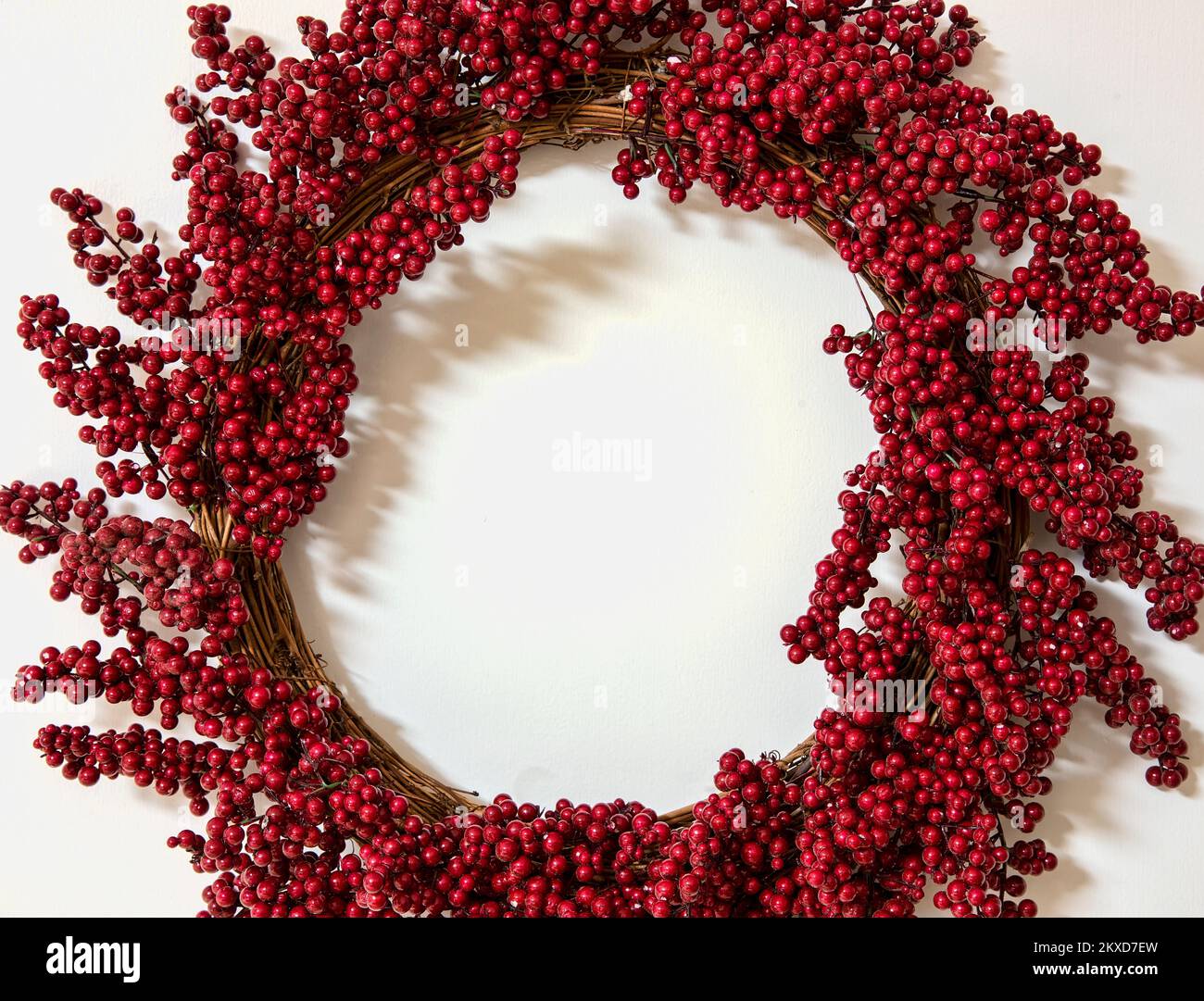 Red berry wreath on grapevine on a white background, room for holiday text Stock Photo