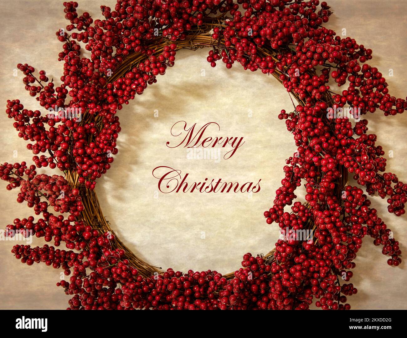 Red berry wreath on grapevine, with Merry Christmas text and rustic background Stock Photo