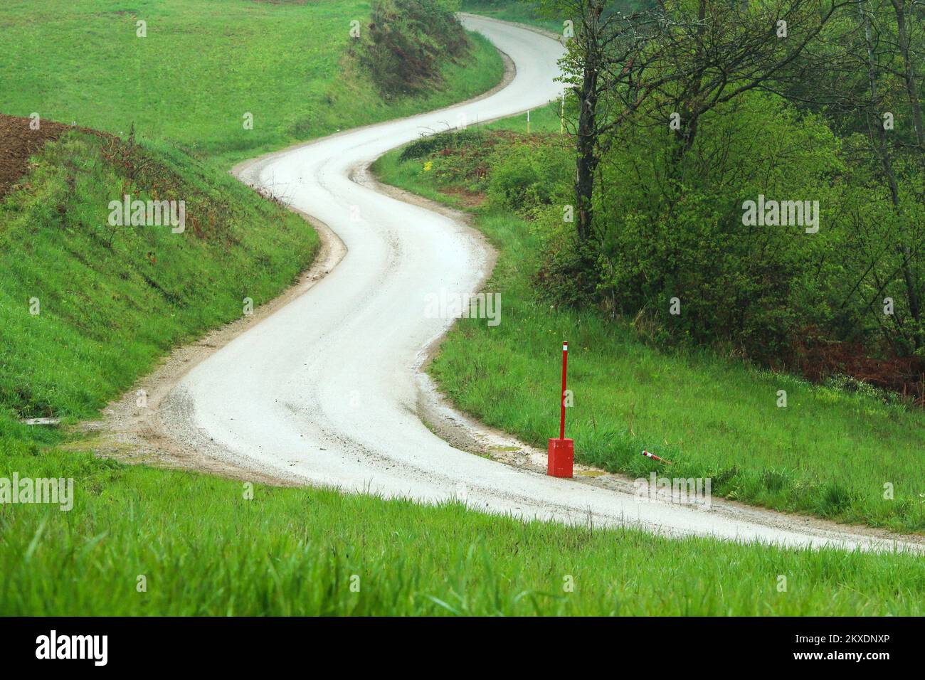 The picture of the part of the road used for the rally event. One anti cut post with a concrete block is inside the curve. Stock Photo