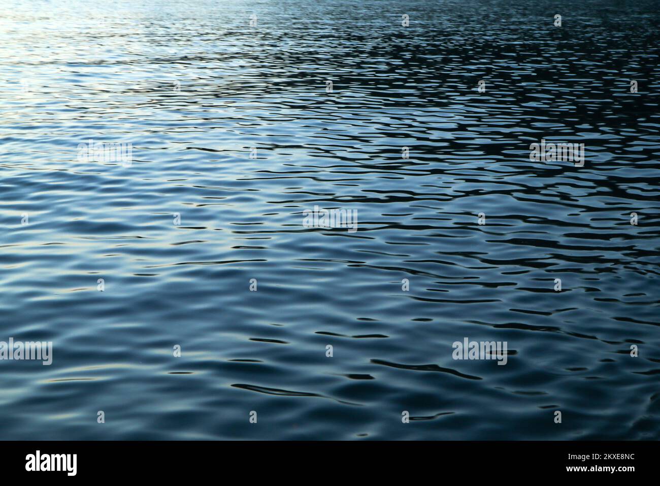 The detail of the calm surface of the sea with the small waves during the evening while sun went already down and the blue shades came. Stock Photo