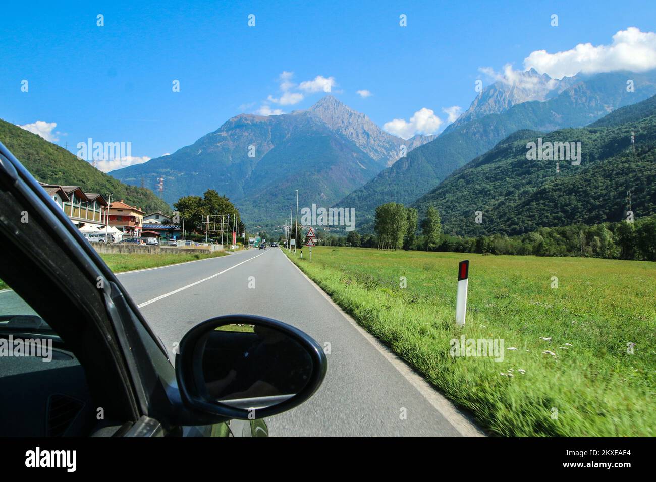 Driving the car towards the alpine valley in Italy during the summer vacation trip. Stock Photo
