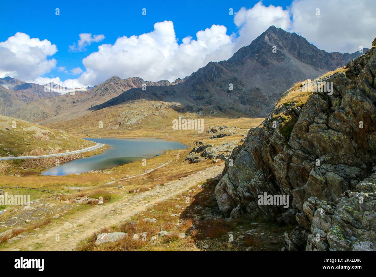 The scenic view of the italian Alps at the Passo di Gavia summit. Nice peaks and a lake below during the sunny day. Stock Photo