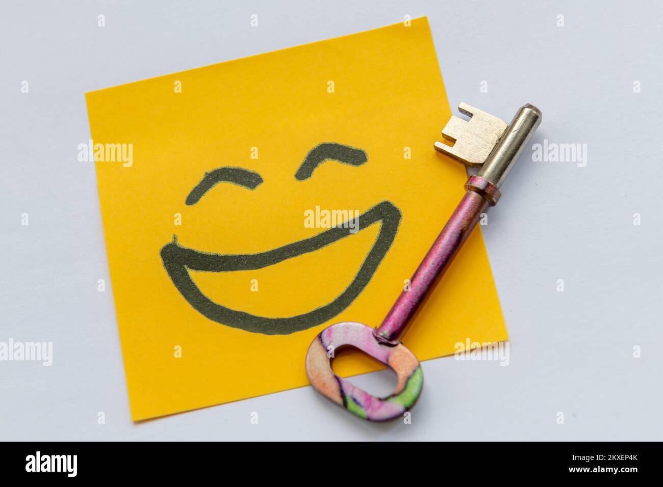 A key to happiness concept with a key and hand drawn happy face isolated in a white background