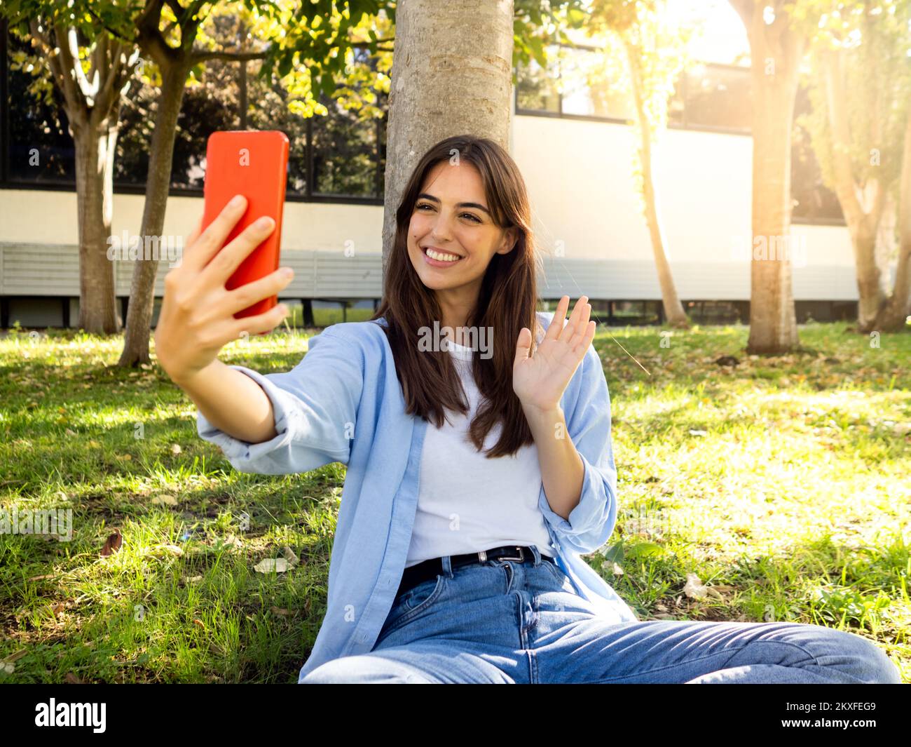 Smiling Spanish young woman making a video call in a park with a smart