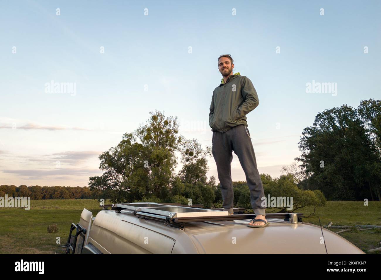 Man posing happily on top of his camper van Stock Photo