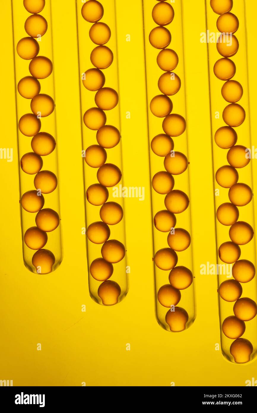 Gel cap vitamins in a glass test tube on a yellow background Stock